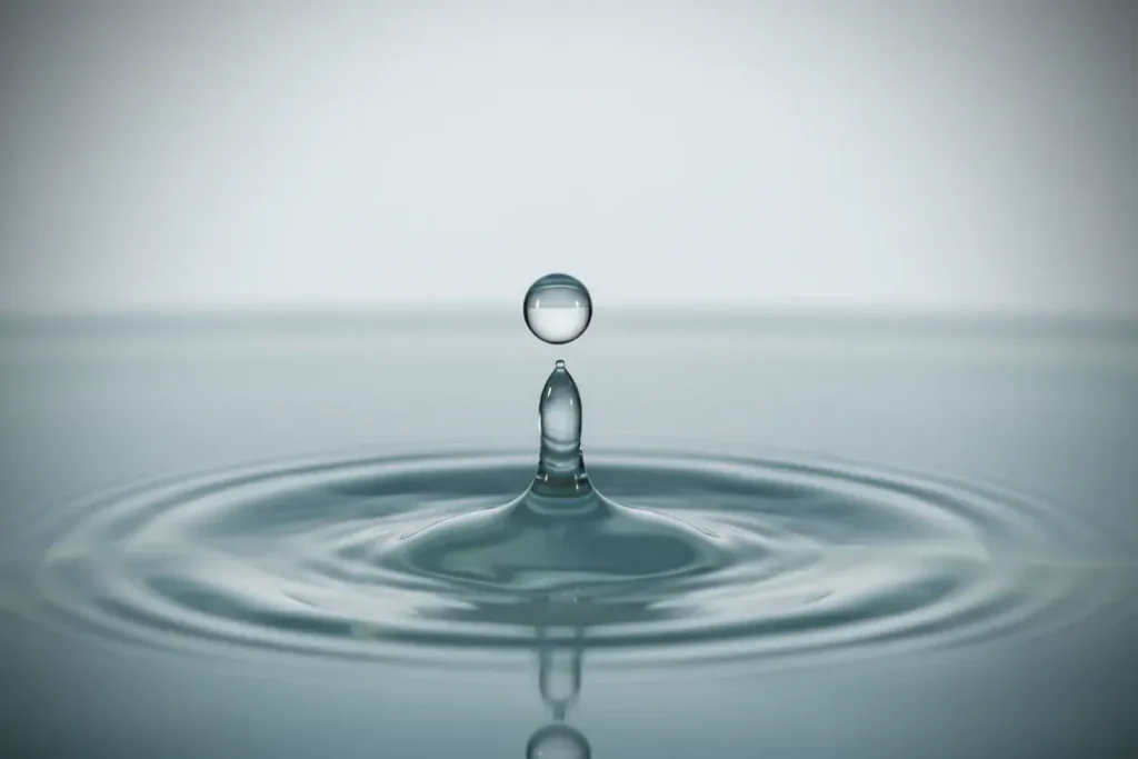 Water droplet creates gentle concentric ripples on a calm surface, symbolizing steady, unobtrusive benefits communication rhythm.
